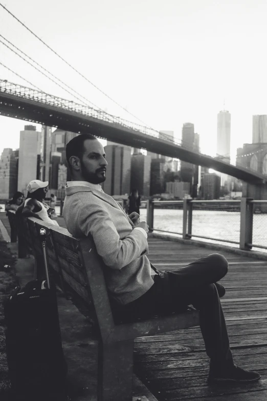 the man is sitting on the bench overlooking a body of water