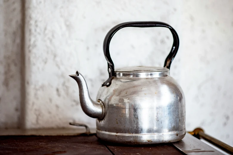 a silver kettle sitting on top of a wooden table