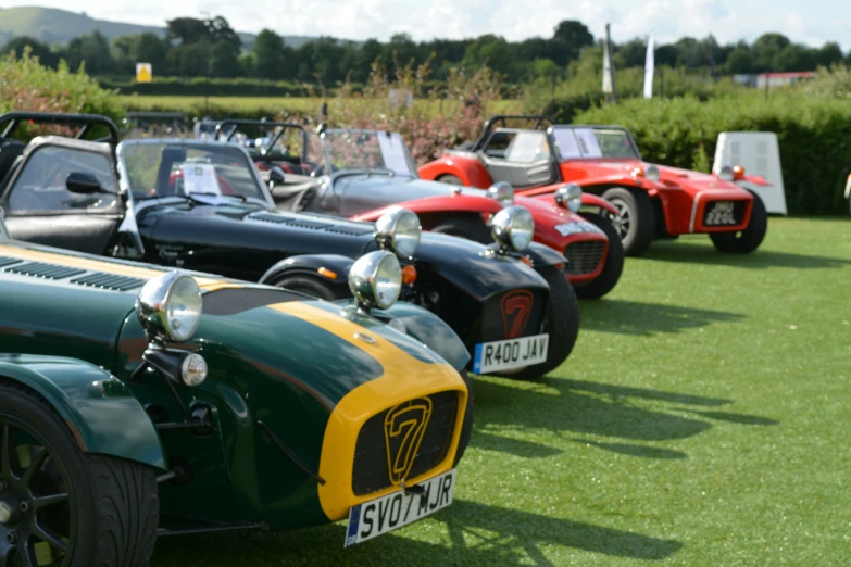 several vintage cars lined up in rows on the grass