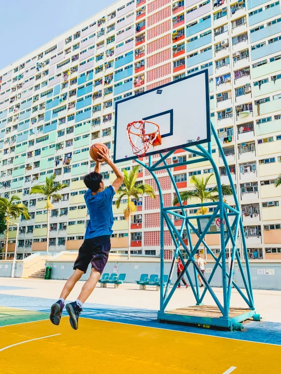 man in shorts is playing basketball outside on a yellow court