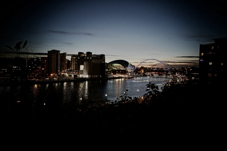 nighttime over a river near tall buildings and ferris wheel