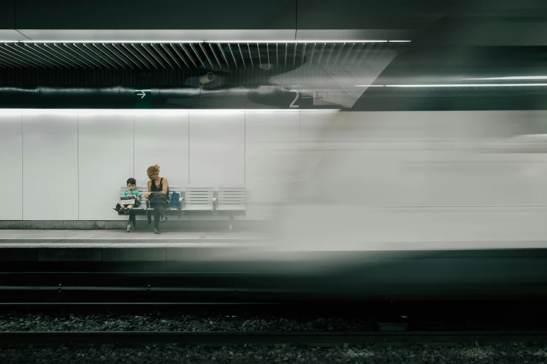 people on a bench watching the train pass by