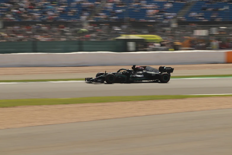 a car racing on the track next to the large crowd