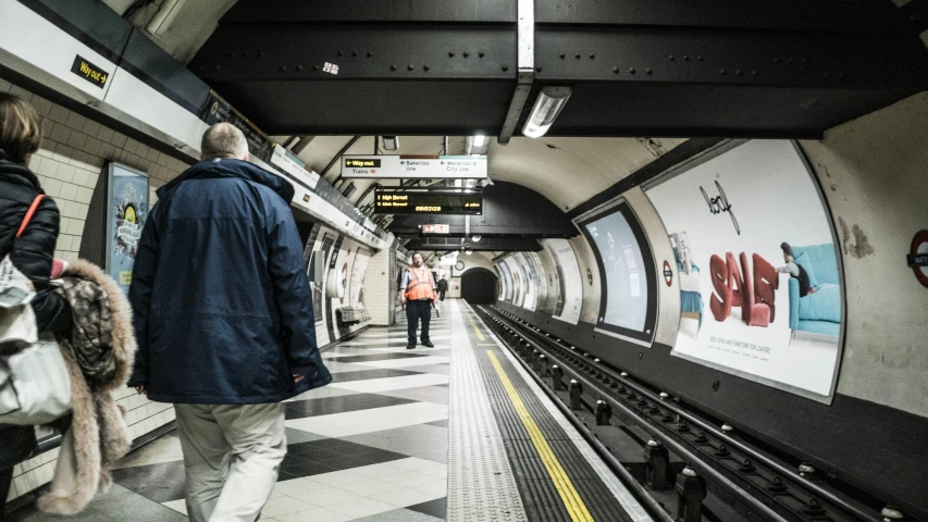 there are two people walking on the platform at the station