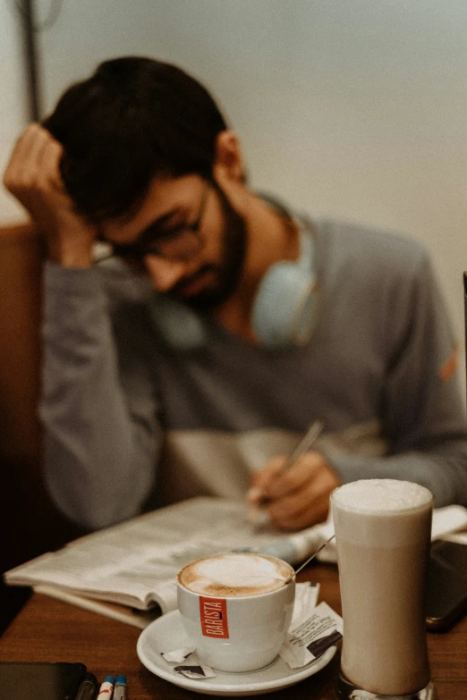 a man writing soing while drinking coffee in front of him