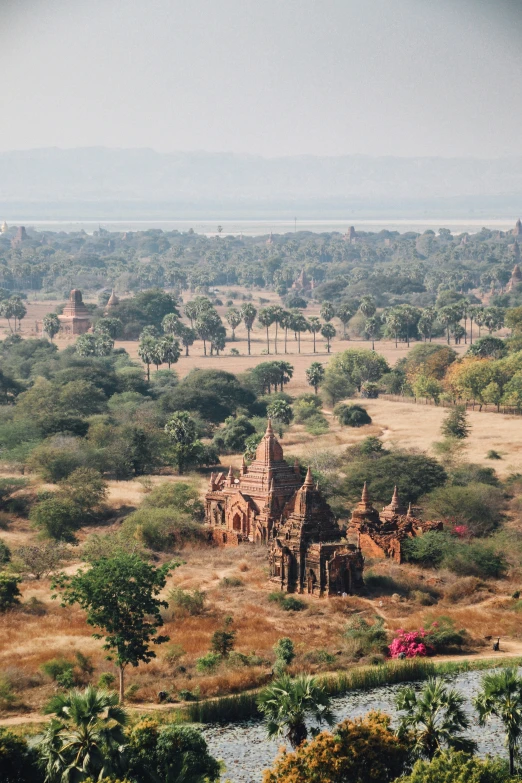 an old temple sits in a desert, with trees around it