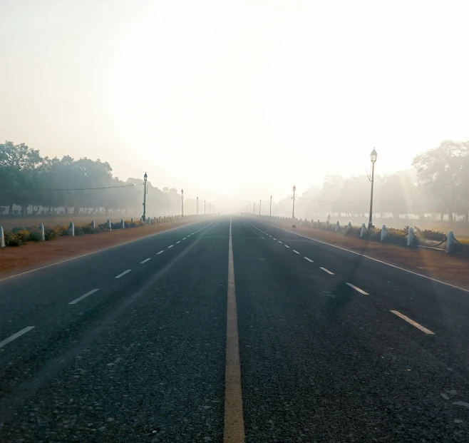 the sun is peeking out from the fog covered street