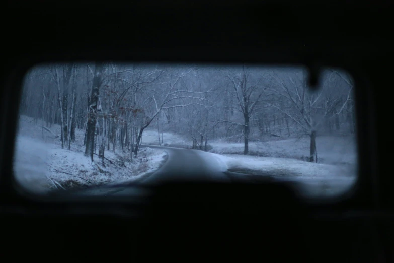 the inside of a car window with trees and snow