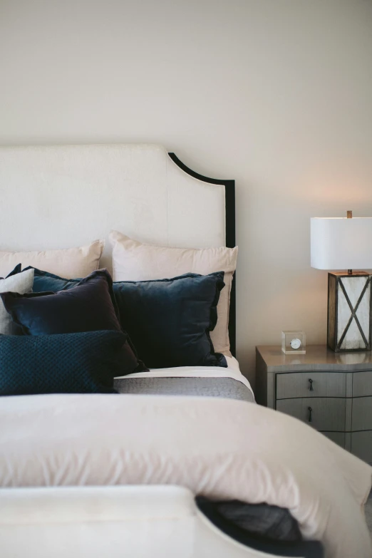a clean, white bed with blue and grey pillows