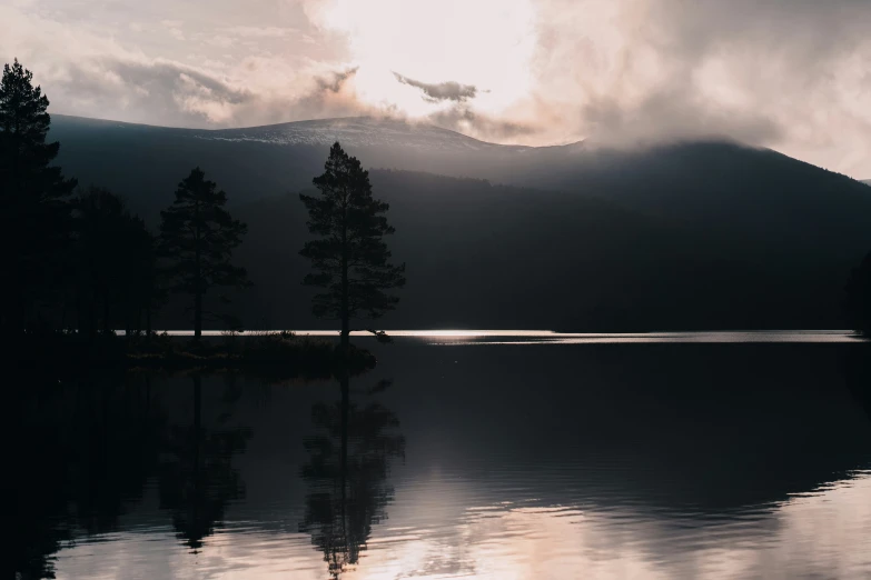 the sun is setting on the mountain range above a lake