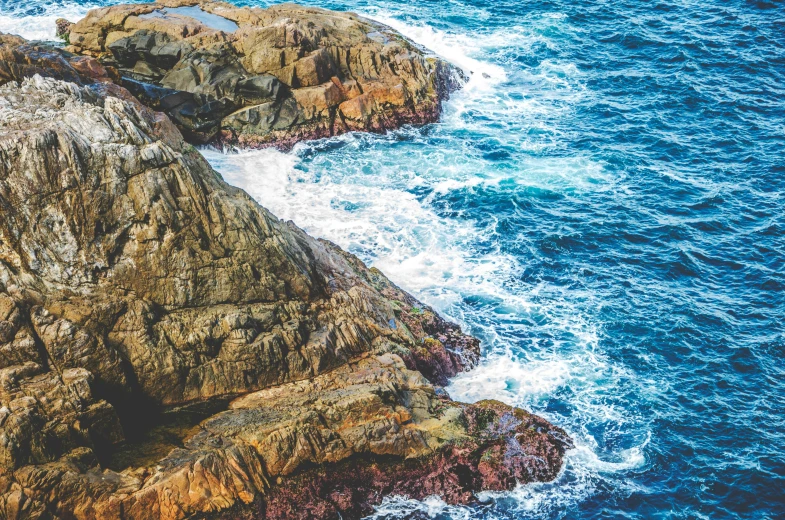 a scenic view of rocks, foaming water and some distant blue sky