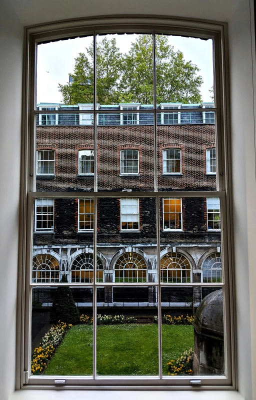 a window with a building through it, looking out at grass