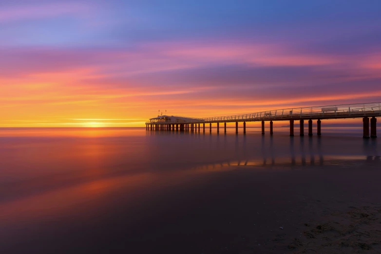 the pier is long and it looks to be an impressive sunset