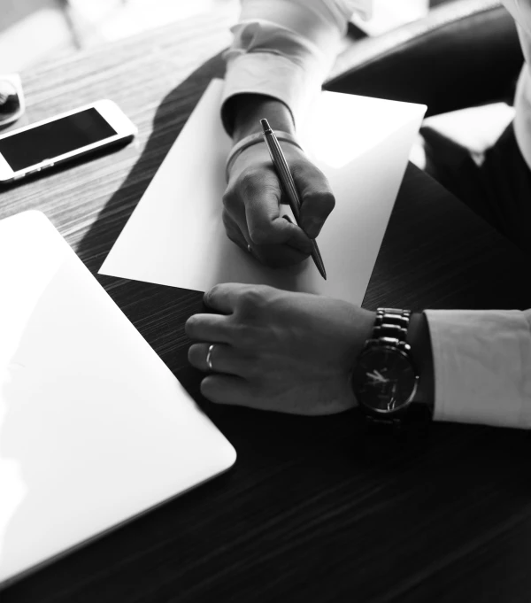 a person is sitting at a desk writing on paper