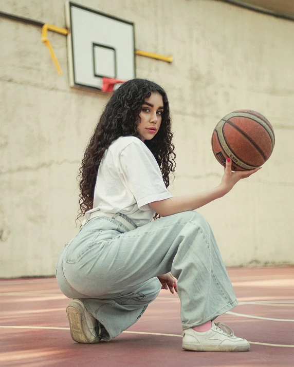 a woman kneeling on the court holding a basketball