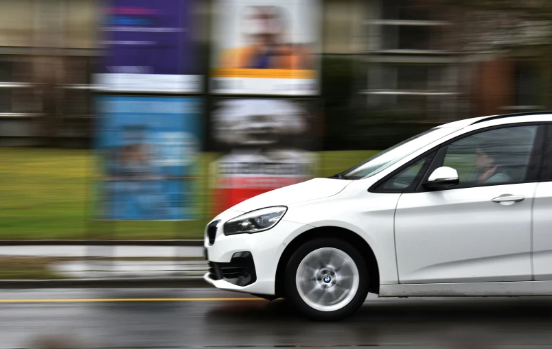 a white car drives down the street on a rainy day