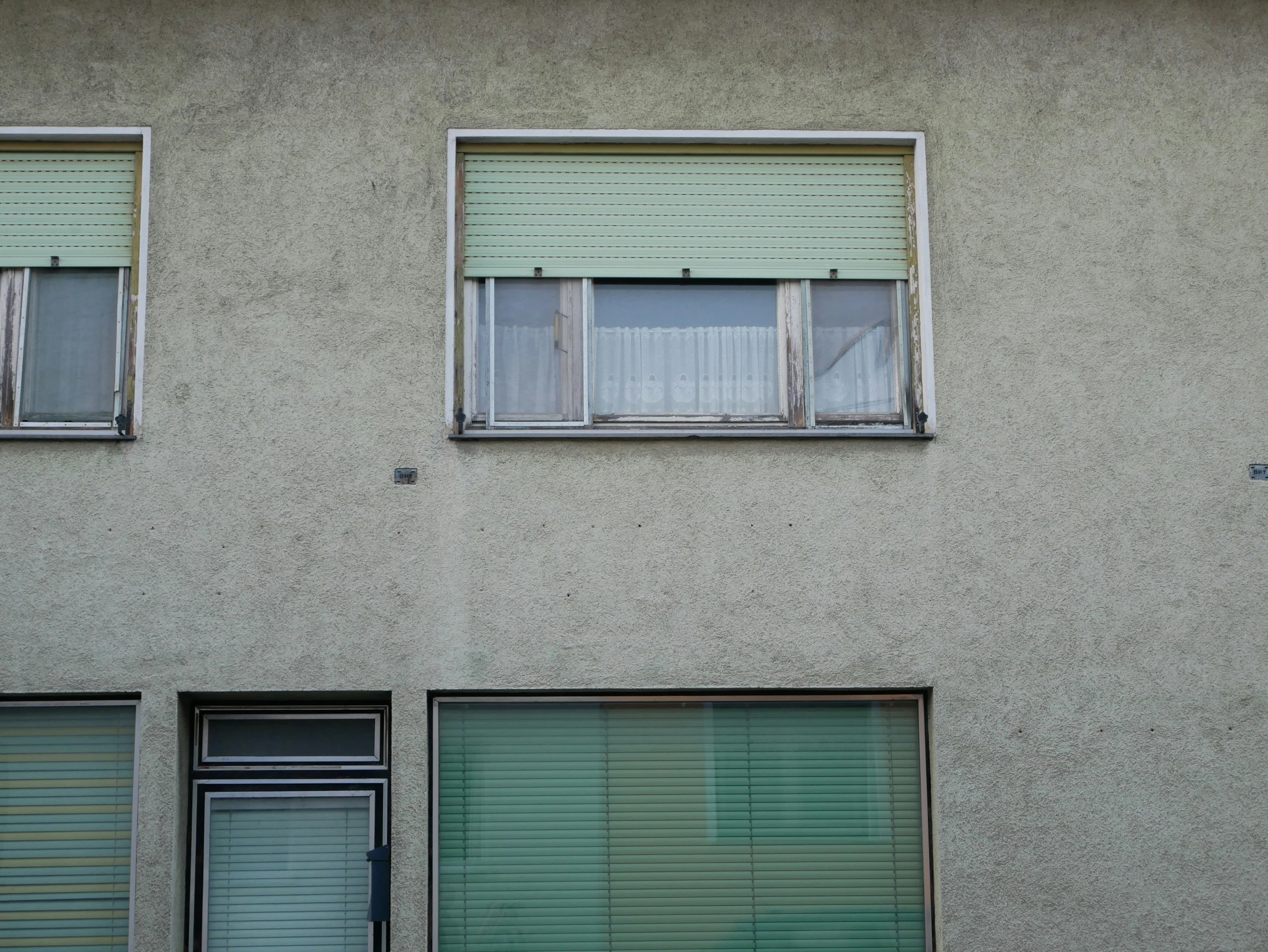 two empty windows that are above a window with no curtains