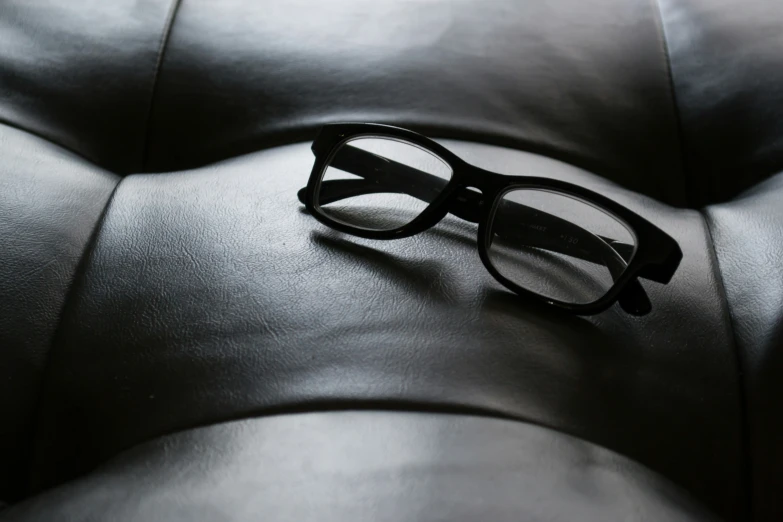 a black eyeglass sitting on top of a chair
