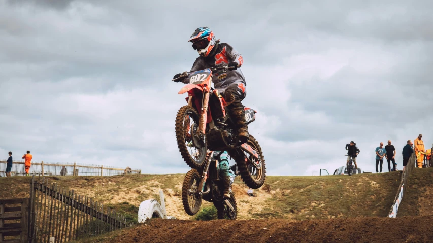 motorcycle rider jumping over dirt hill with crowd watching