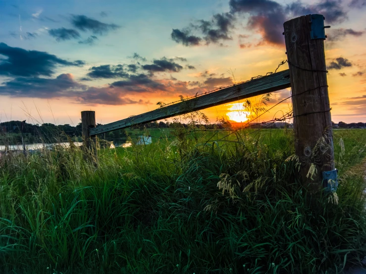 a sunset over a body of water with fence on each side