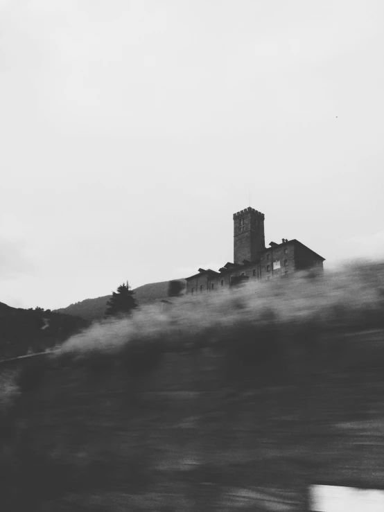 a black and white pograph of an old building on a hill