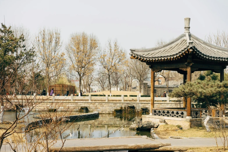 a beautiful asian pavilion sits at the edge of a small pond