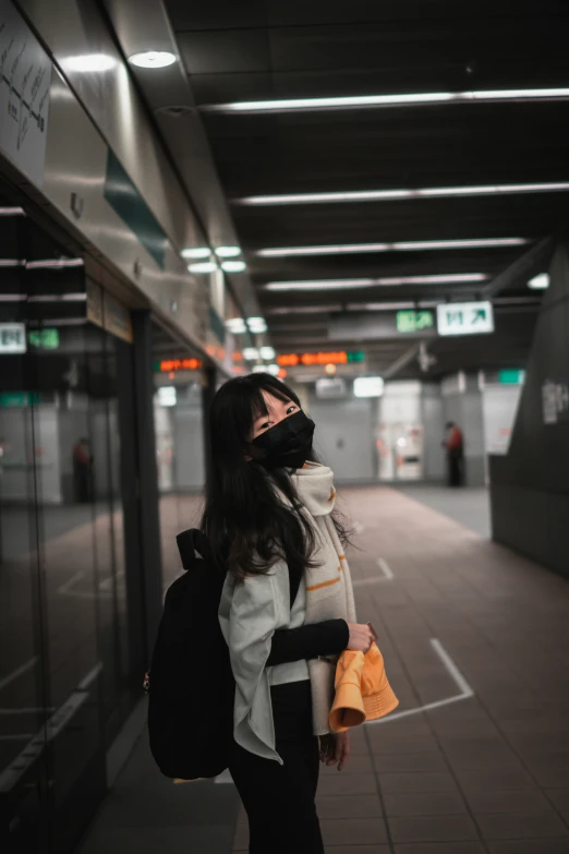 a woman standing at a subway station with her backpack in tow