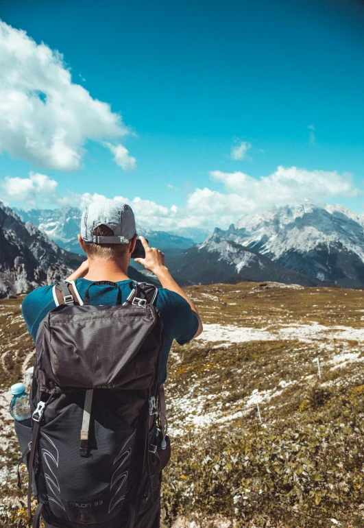 a man in a backpack standing on top of a mountain looking at snow