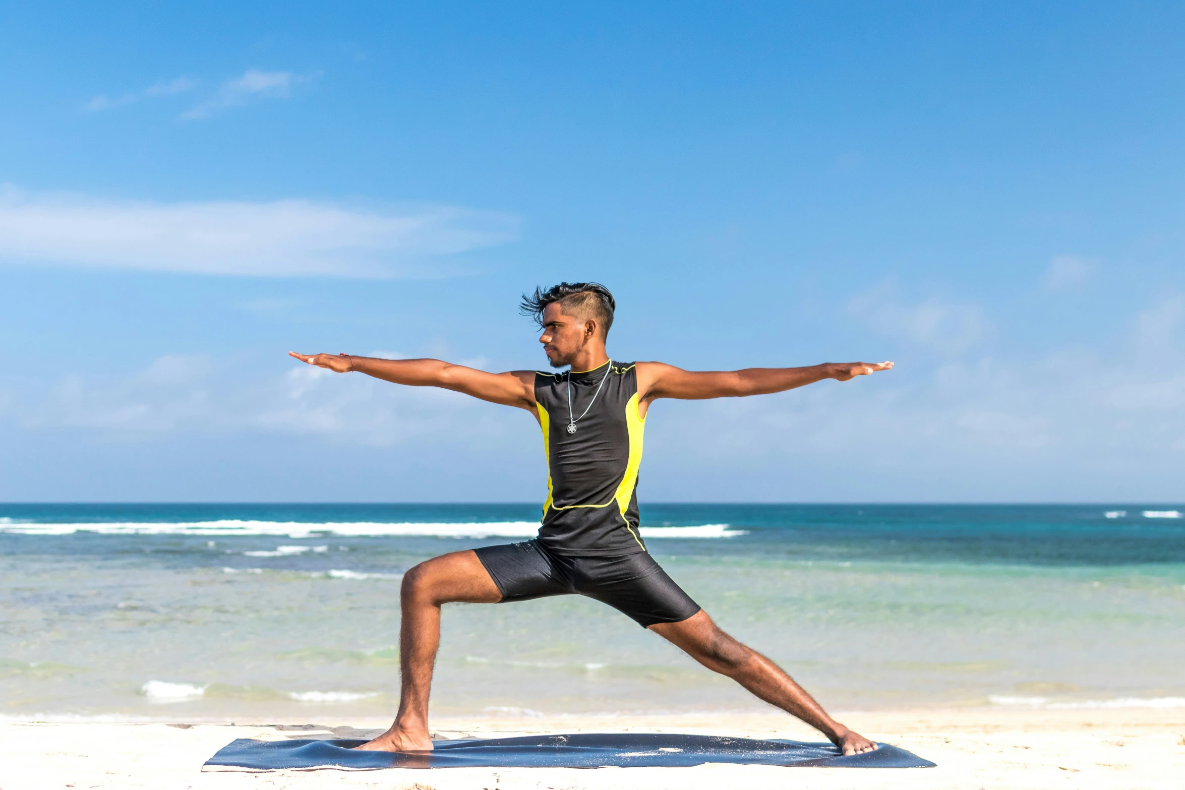 a person with their arms outstretched doing a yoga pose on the beach