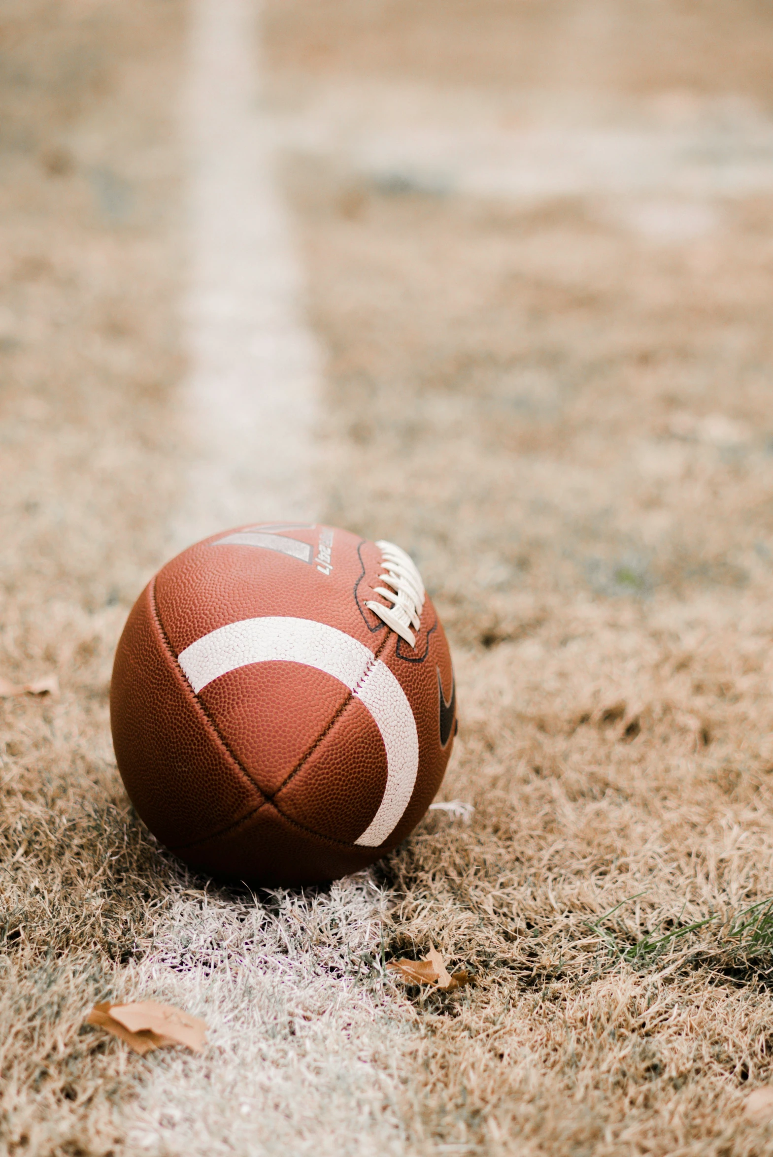 a football that is on the ground by some grass