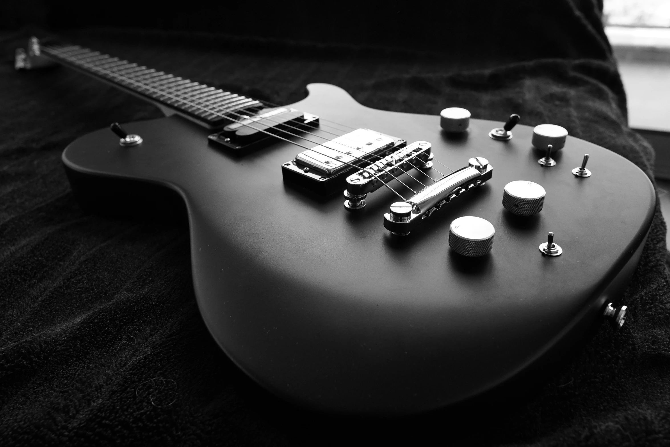 a guitar sits on a black surface with ons and picks on top