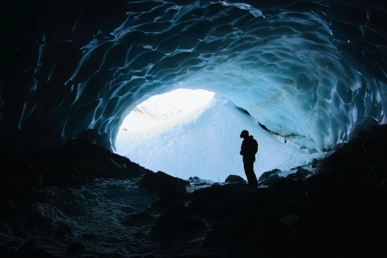 a person stands at the entrance to a ice cave