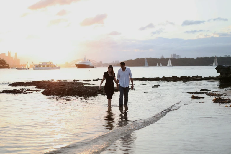 couple walking on beach in front of large body of water