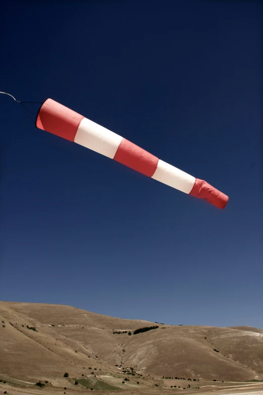 a large kite with a white and red stripe in the sky