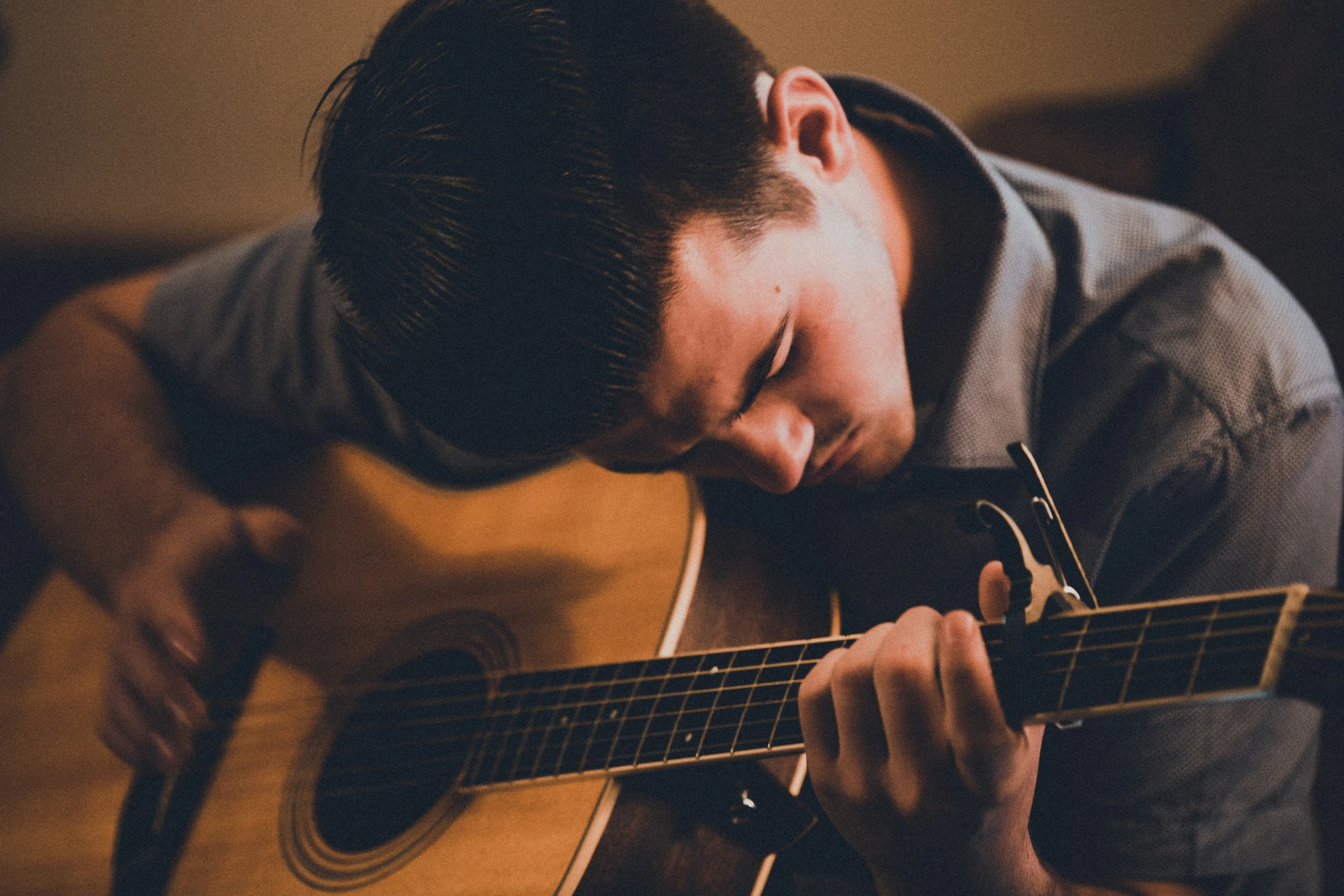 the man is playing an acoustic guitar in his room