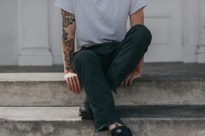 man in grey shirt sitting on steps with leg tattooed