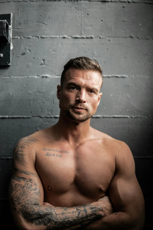 a muscular man wearing tattoos poses for the camera