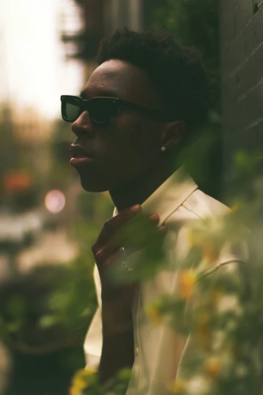 young man wearing sunglasses leaning against wall