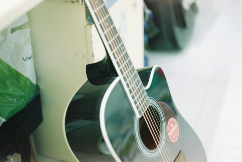 a small guitar propped up against the side of a cabinet