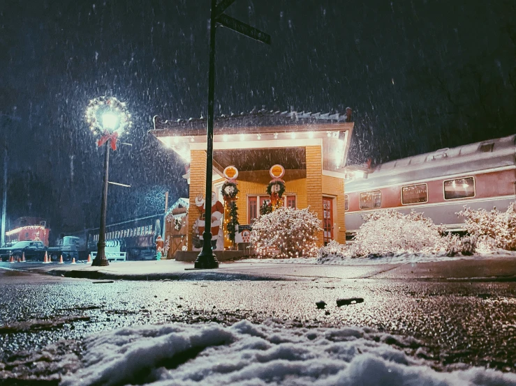 a snow covered street corner at night with a train