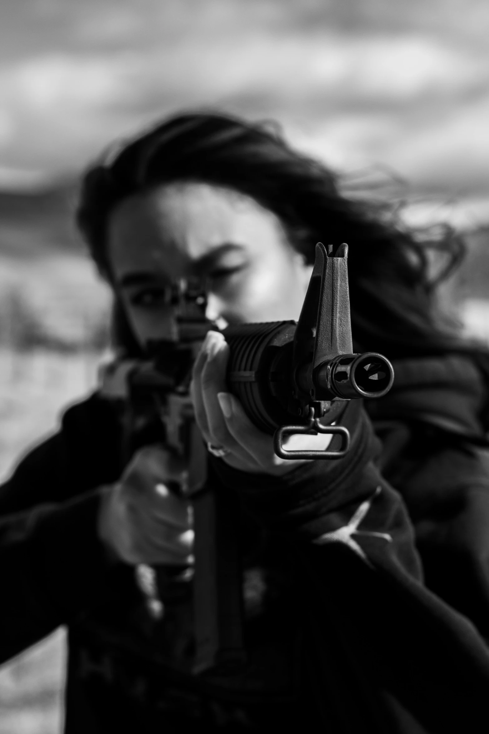 woman aiming a gun at the camera with her scarf on