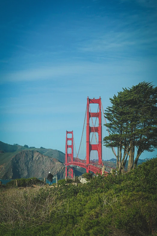 a bright red bridge is surrounded by green hills