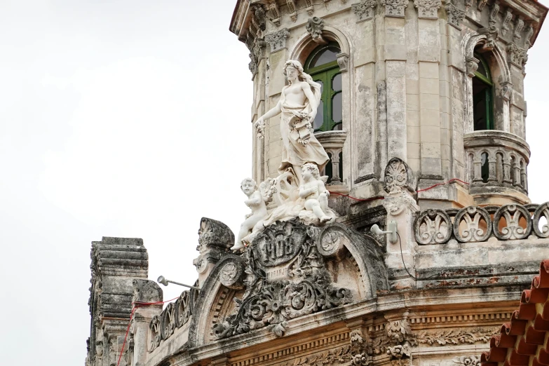 an ornate building with clock and angel sculpture at the top