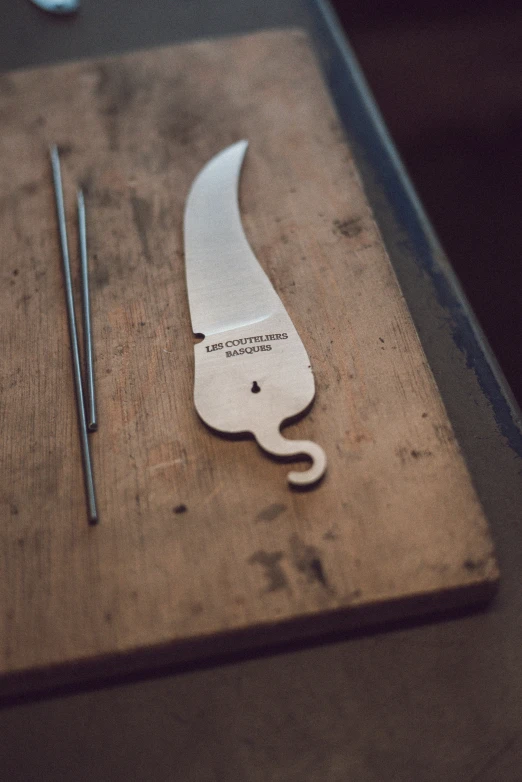 a knife is lying on the table next to a pair of needles