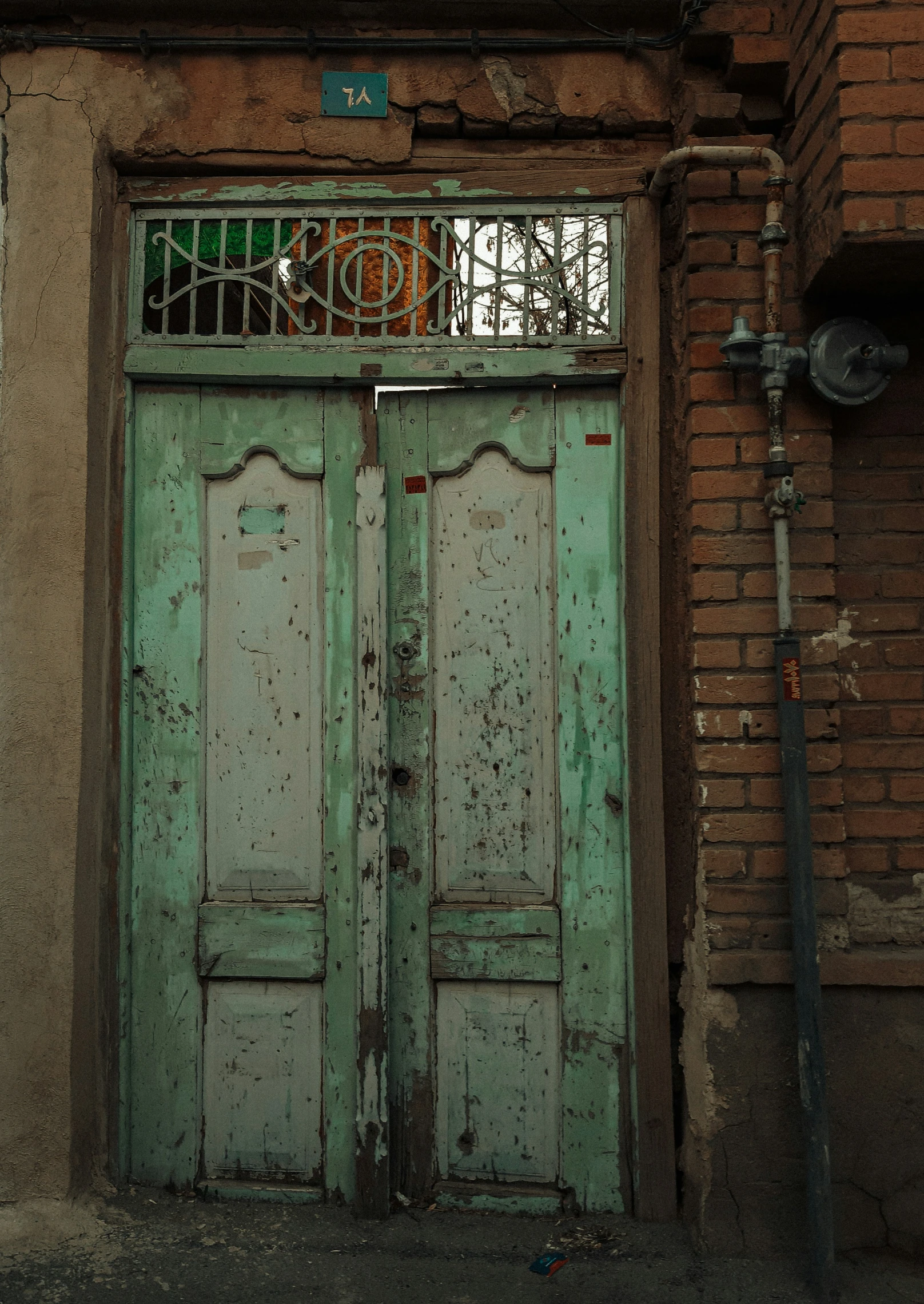 a dilapidated door with bars on it stands by a window