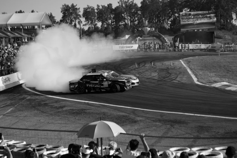 a car drifts along the dirt in front of spectators