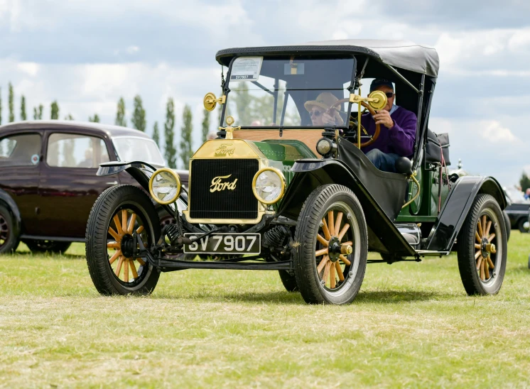 antique car with gold wheels on display in grassy area
