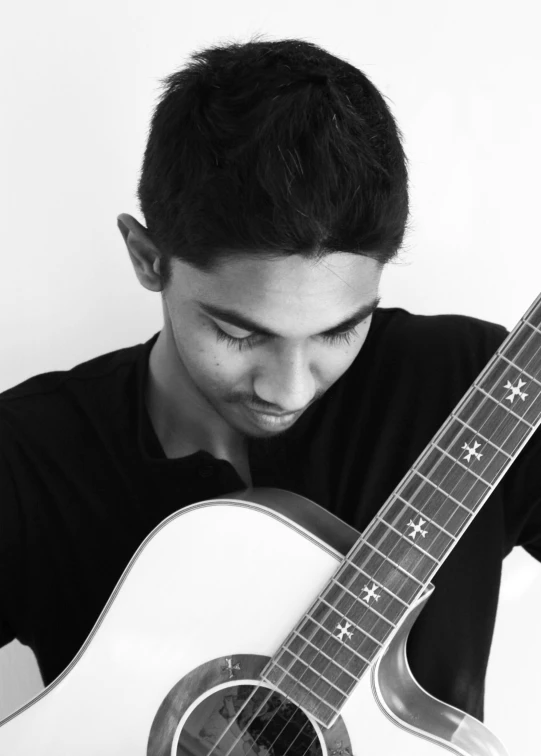 a young man is sitting and playing the guitar