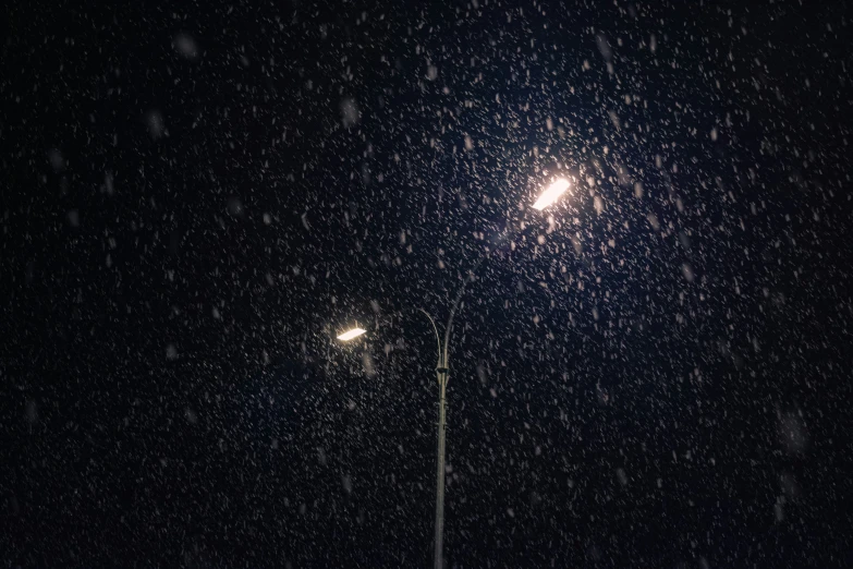 a street lamp on a snow covered street in the night