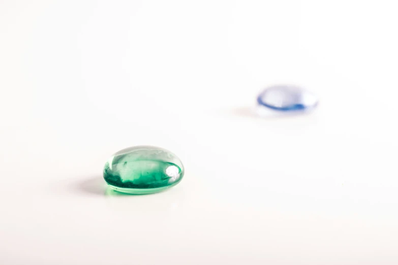 two green stones next to each other on a white surface